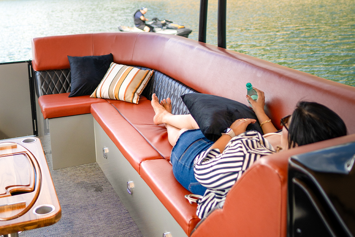 Mulher descansando confortavelmente no sofá de couro caramelo do convés do Pontoon Boat