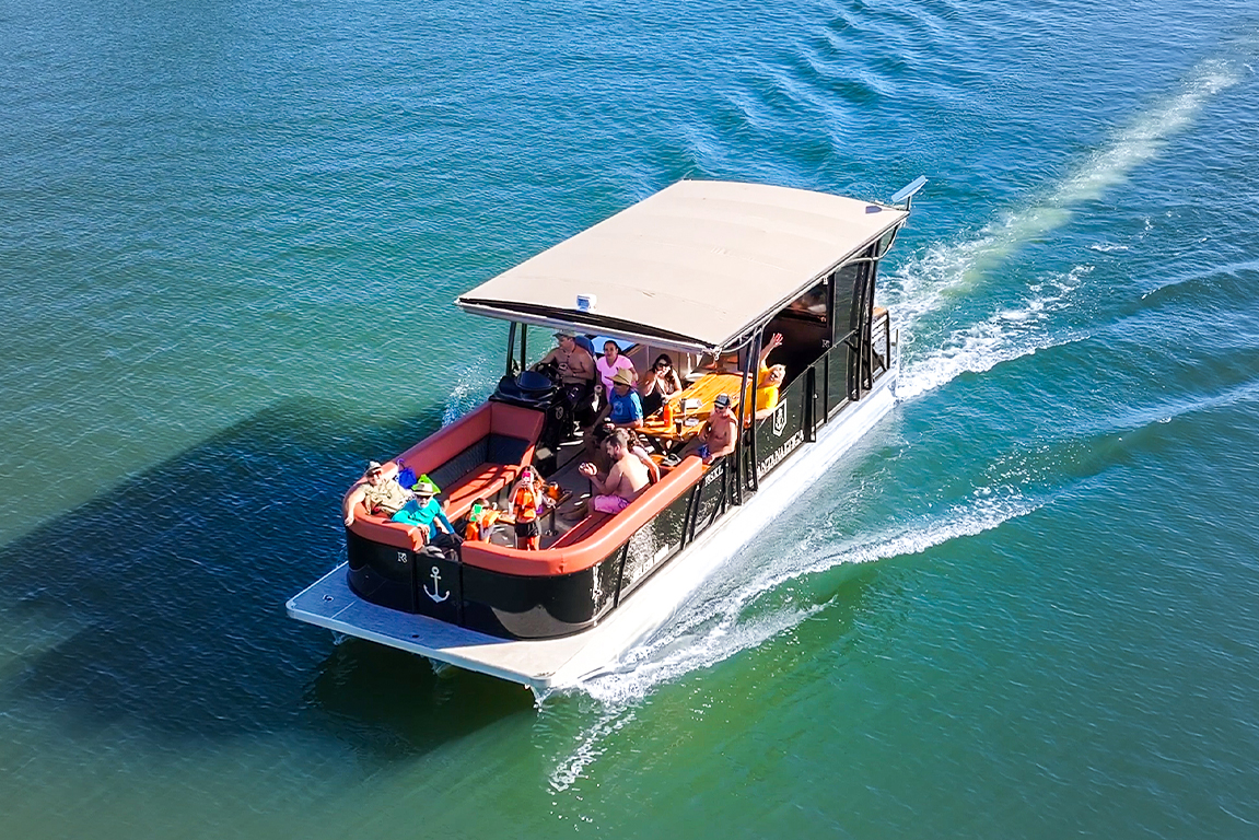 Vista aérea do barco Pontoon R5 SXL da Pantanaltica navegando com uma família a bordo, mostrando o amplo espaço do convés.