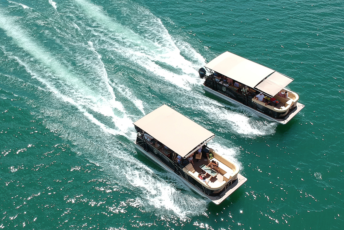 Vista aérea de drone mostrando dois barcos Pontoon Pantanaltica navegando lado a lado em águas verdes turquesa